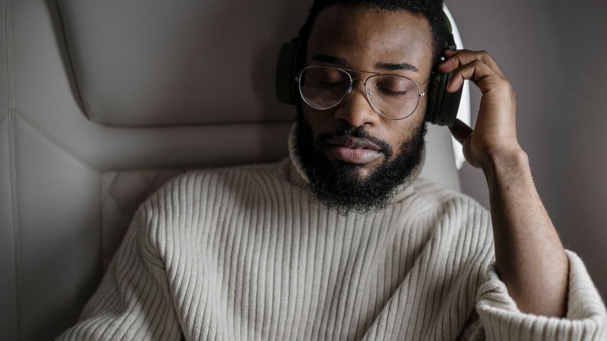 Traveler using best tech gifts for travelers 2026 noise cancelling headphones on plane