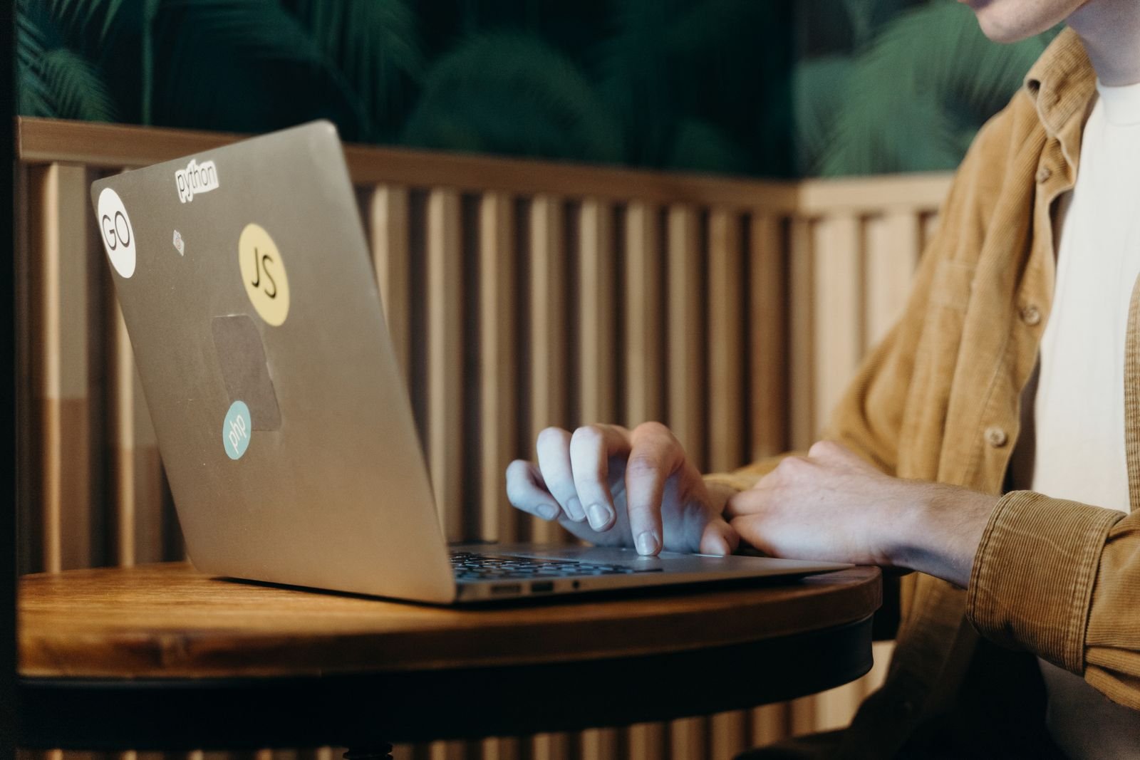 Person working on a laptop in a cafe to extend laptop battery life on the go