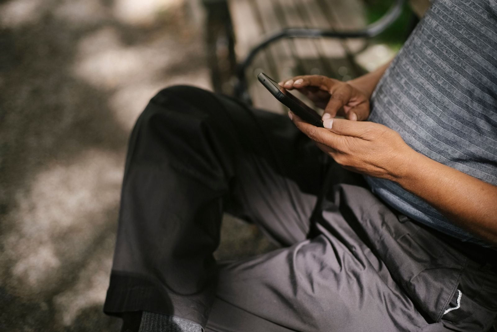 Person using a smartphone while sitting on a bench outdoors