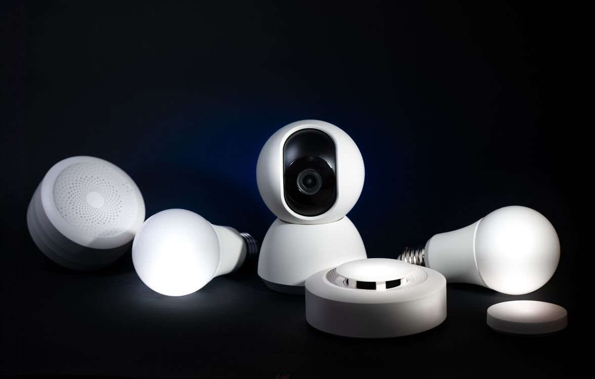 Smart home security camera surrounded by smart bulbs and a smoke sensor on a black background